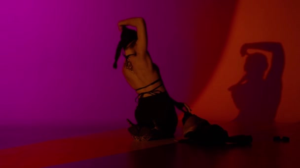現代の振付とダンスクリエイティブコンセプト 女性ダンサーの肖像画 赤い鮮やかなネオンライトバックグラウンドの床のスタジオでレザートップとハイヒールで踊る女性ダンサーを魅了 — ストック動画