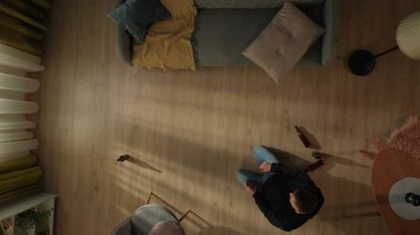 Oturma odasında dizlerinin üstünde bira şişesiyle oturan sarhoş bir adamın en iyi görüntüsü. Alkolizm. Umutsuzluk. Alkol bağımlılığı tedavisi