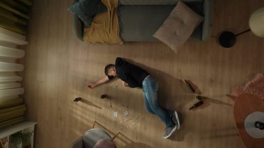 Oturma odasında, boş şişelerin, hapların ve şırıngaların arasında yatan bir adamın en iyi görüntüsü. Adam uyuşturucu aldıktan sonra yoksunluk çekiyor. Alkolizm ve uyuşturucu bağımlılığı akli ve zihinsel ve