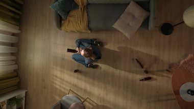 Oturma odasında sarhoş bir kadının en iyi görüntüsü. Kadın dizlerinin üzerine çöküp şişeden bira içiyor. Alkolizm. Umutsuzluk. Alkol bağımlılığı tedavisi