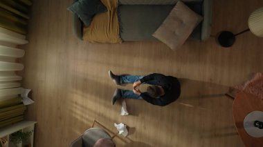 Oturma odasının zemininde buruşmuş faturaların yanında oturan bir adamın en iyi görüntüsü. Adam kamu borcu için endişeleniyor.