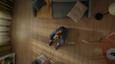 Oturma odasının zemininde oturan bir kadının en üst görüntüsü. Bunalımlı kadın, başı aşağıda acı çekiyor. Yalnızlık, mutsuzluk, depresyon, umutsuzluk kavramı