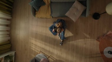 Oturma odasının zemininde elinde akıllı bir telefonla kanepenin yanında oturan bir kadının en iyi görüntüsü. Telefonda konuşan kadın.