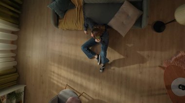 Oturma odasının zemininde elinde akıllı bir telefonla kanepenin yanında oturan bir kadının en iyi görüntüsü. Telefonda konuşan kadın.