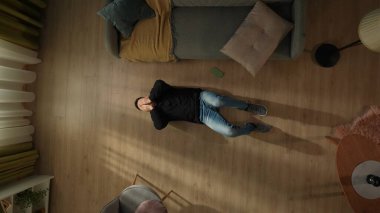 Oturma odasının zemininde telefonunun yanında yatan bir adamın en üst görüntüsü. Adam yüzünü avuçlarının içine sakladı, online bir oyunu kaybettiği için üzgündü. Gadget bağımlılığı