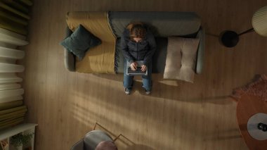 Oturma odasında kucağında dizüstü bilgisayarla oturan bir kadının en iyi görüntüsü. Serbest İşçi, uzak çalışma