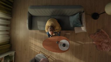 Tek başına içki içen bir kadının en iyi görüntüsü. Ekoseyle kaplı bir kadın oturma odasında bir sehpanın önünde elinde bir şişe alkolle oturuyor. Alkolizm. Alkol bağımlılığı tedavisi