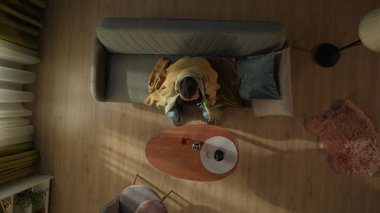 Oturma odasında tek başına içki içen bir adamın en iyi görüntüsü. Ekoseyle kaplı, yüzünü avuçlarına saklayan bir adam kahve masasının önündeki kanepede elinde bir şişe alkolle oturuyor. Alkolizm