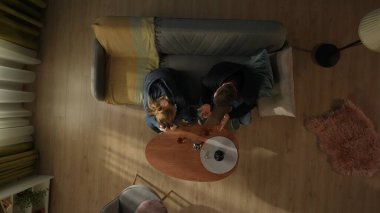 Oturma odasındaki kanepede oturan bir çiftin bir şişe alkol ve bardakla birlikte kahve masasının önündeki görüntüsü. Bir erkek ve bir kadın alkol yardımıyla sorunlardan kaçıyorlar. Alkolizm