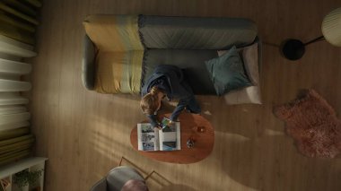 Oturma odasındaki kanepede oturan bir kadının kahve masasının önünde elinde bir şişe alkol ve bardakla görüntüsü. Bir kadın fotoğraf albümüne bakıyor. Boşanma, ayrılma.