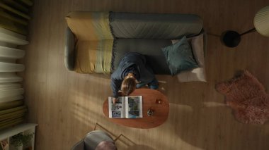 Oturma odasındaki kanepede oturan bir kadının kahve masasının önünde elinde bir şişe alkol ve bardakla görüntüsü. Bir kadın fotoğraf albümüne bakıyor. Boşanma, ayrılma.