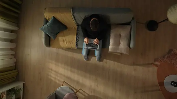 リビングルームに座っている男のトップビュー 彼女の膝の上にラップトップとソファーで フリーランサー リモートワーク — ストック写真