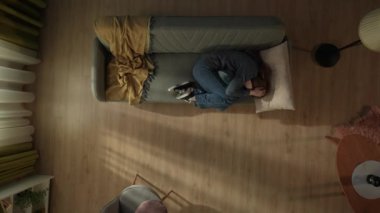 Oturma odasındaki kanepede uzanmış yastığa sarılan bir kadının en iyi görüntüsü. Depresyondaki kadın acı çekiyor, ağlıyor. Yalnızlık, mutsuzluk, depresyon, umutsuzluk kavramı