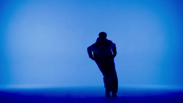 青い白い背景の写真です シルエットのヒップホップの方向にダンスの動きを示す男性を描きます ストリートスタイルの服装 それは明るく プラスチック リズミックです — ストック動画