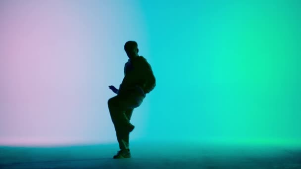ピンク ブルー グラデーションの背景の写真です ヒップホップの方向にダンスの動きを示す男性を描きます ストリートスタイルの服装 それは明るく プラスチック リズミックです — ストック動画