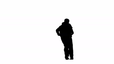 Beyaz bir arkaplanda, siluet giymiş bir adam dans ediyor. Hip hop yönündeki çeşitli dans hareketlerini gösteriyor. Plastik, ritmik, profesyonel. Yavaş çekim