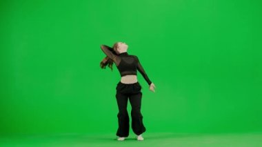 Modern koreografi ve dans stili yaratıcı konsept. Kadın dansçı portresi. Siyah kıyafetli çekici bir kız krom anahtar yeşil ekran arka planında çağdaş dansın enerjik unsurlarıyla dans ediyor..