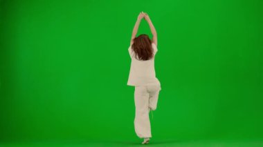 Modern koreografi ve dans stili yaratıcı konsept. Kadın dansçı portresi. Beyaz elbiseli çekici bir kız Chroma Key Green Screen arka planında çağdaş dansın dinamik unsurlarıyla dans ediyor..