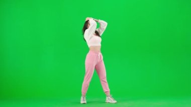 Modern koreografi ve dans stili yaratıcı konsept. Pembe pantolonlu çekici bir kadın stüdyoda krom anahtar yeşil ekranda şehvetli caz funk koreografisi yapıyor. Reklam alanı modeli.