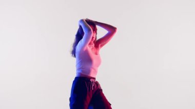 Modern koreografi ve dans stili yaratıcı konsept. Kadın dansçı portresi. Kırmızı ve mavi ışıklı, enerjik caz funk dansı yapan çekici bir kadın. Stüdyoda beyaz arka planda izole edilmiş..