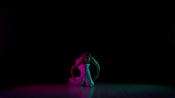 现代编舞和舞蹈风格的创意理念 女舞蹈家的画像 穿着休闲装的迷人女孩 穿着浅绿色和粉色霓虹灯 黑色背景 跳着现代现代舞 — 图库视频影像