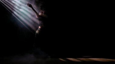 Modern koreografi ve dans stili yaratıcı konsept. Kadın dansçı portresi. Stüdyoda dans eden cazcı kadın funk dansı elementleri dumanla dolu, siyah arkaplanda ışık huzmeleri.