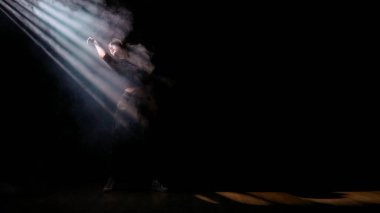 Modern dans koreografisi yaratıcı reklam konsepti. Çekici kadın silueti dans eden caz funk dans elementleri karanlık stüdyoda dumanla dolu, yan taraftan gelen ışık ışınları, siyah arka plan.