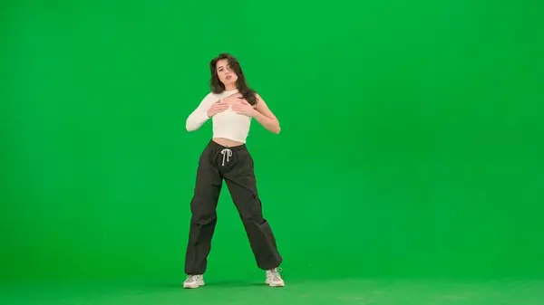 現代ダンス振付クリエイティブ広告コンセプト スタジオでクロマキーグリーンスクリーンの背景にジャズファンクダンスのポーズに立っているホワイトトップとブラックパンツの魅力的な女性 — ストック写真