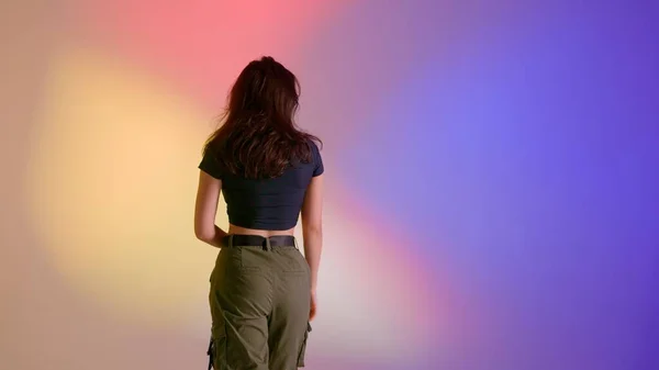 现代舞编舞创意广告的概念 穿着上衣和卡其裤的迷人女人在镜头前摆姿势 把她的背靠得很近 在工作室里跳爵士舞 在霓虹灯的背景下与世隔绝 — 图库照片