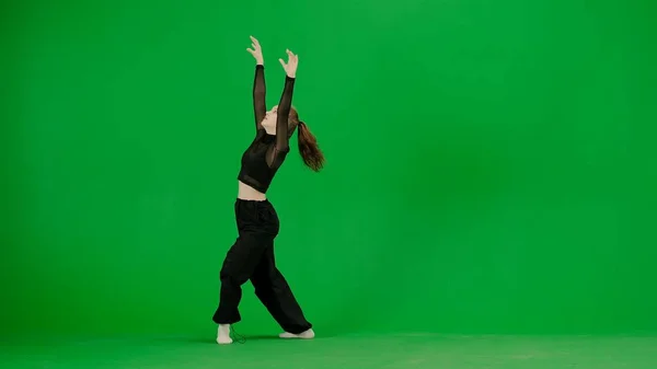 现代创意舞蹈和舞蹈概念 女舞蹈家的画像 穿着黑色服装的年轻貌美的姑娘在色彩缤纷的绿色银幕背景上跳着现代舞 — 图库照片