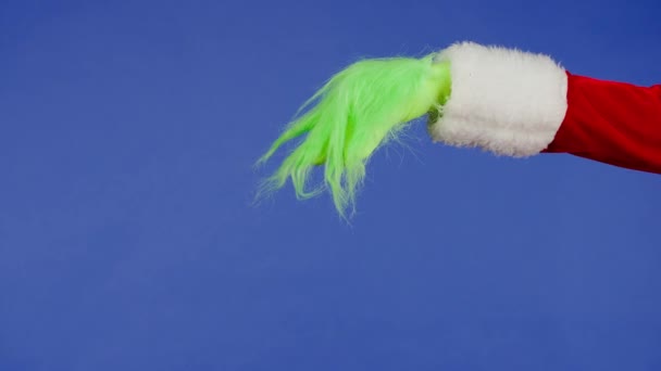 グリンコックの緑色の髪の手は 隔離された青色の背景に対して何かを保持しているようです ギフトスナッチャーコスプレ クリスマスと新年のお祝いコンセプト ブルースクリーン クロマキー — ストック動画