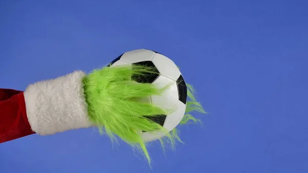 Grinchs Grønne Hårete Hender Holder Fotballball Blå Isolert Bakgrunn Gavefanger – stockfoto