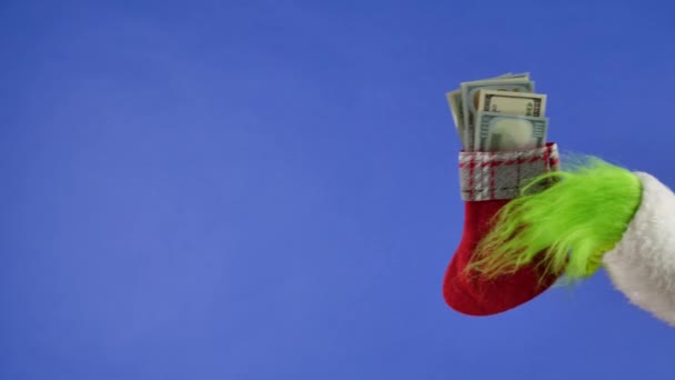 Zelená Ruka Grinchových Drží Vánoční Ponožku Dolarovými Bankovkami Modrém Izolovaném — Stock video