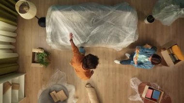 Yeni ev ve gayrimenkul yaratıcı reklam konsepti. Taşınma ve tahliye. Üst kattaki oturma odası. Kadın akıllı telefondan video kaydediyordu. Erkek, yeni dairesindeki kanepeden filmi nasıl çıkarıyordu?.