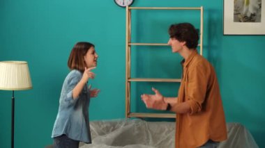 Yeni ev ve gayrimenkul yaratıcı reklam konsepti. Taşınma ve tahliye. Oturma odasının kapağını kapatın. Yeni dairede bir çift, mutlu yüz ifadesi olan bir adam kızı ellerinin arasında tutuyor ve etrafında dönüyor..