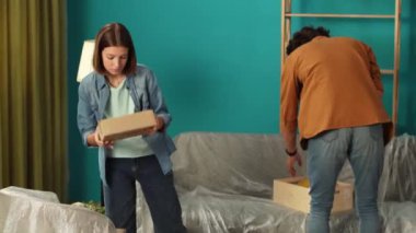 Yeni ev ve gayrimenkul yaratıcı reklam konsepti. Taşınma ve tahliye. Oturma odasını kapatın. Birkaç adam ve kadın yeni dairede kutularını boşaltıp etrafa bakınıyorlar..