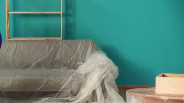 Yeni ev ve gayrimenkul yaratıcı reklam konsepti. Taşınma ve tahliye. Yeni apartman salonunu kapatın. Üniformalı teslimatçı odaya karton kutu ve eşyalar getiriyor..