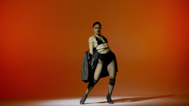 Pomarańczowym Tle Młoda Kobieta Pokazuje Ruchy Taneczne Kierunku Wysokich Obcasów — Wideo stockowe