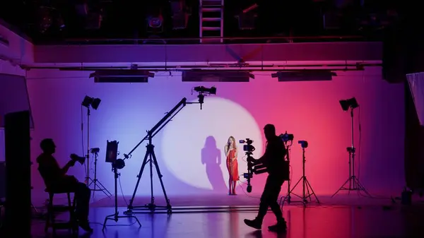 Professional filming pavilion with a white cyclorama. The process of preparing for the shooting of a music video. Director, Cameraman and crew in Backstage