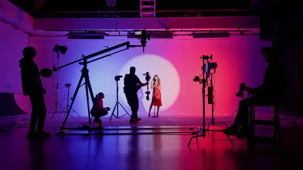 Professional filming pavilion with a white cyclorama. The process of preparing for the shooting of a music video. Director, Cameraman and crew in Backstage