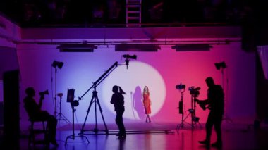 Beyaz siklonamalı profesyonel film köşkü. Bir klip çekimine hazırlanma süreci. Yönetmen, Kameraman ve ekibi sahne arkasında.