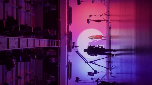 白いサイクロラマでプロの撮影パビリオン ミュージックビデオの撮影のための準備のプロセス バックステージの監督 カメラマン クルー 垂直ビデオ — ストック動画