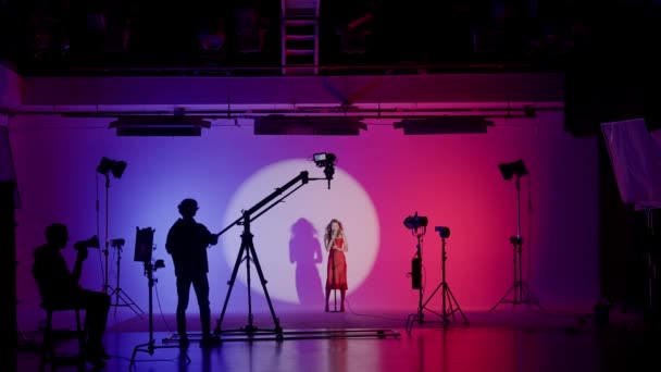 白いサイクロラマでプロの撮影パビリオン ミュージックビデオの撮影のための準備のプロセス バックステージの監督 カメラマン クルー — ストック動画