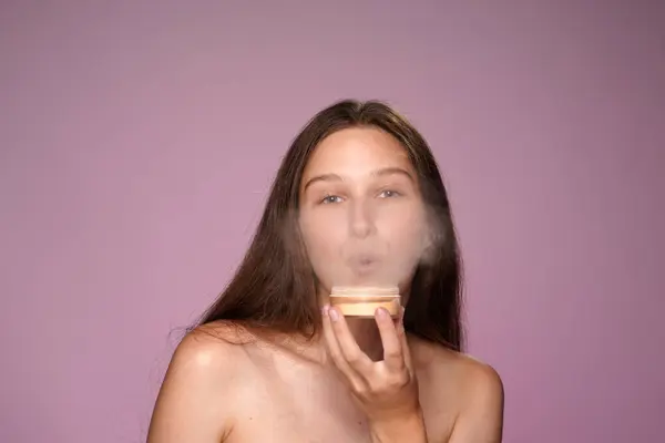ピンクのネオンライトのピンクの背景にスタジオで粉の缶を持つ女性の肖像画が閉じます セミノードの女性が粉を吹いている コンタクトする 化粧品 スキンケアのコンセプト — ストック写真
