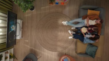 Aile ilişkileri ve ebeveynlik reklamları. Ailecek vakit geçireceğiz. Oturma odasının en iyi manzarası. Anne, baba ve oğul kanepede oturur, TV 'de korku filmi izler, patlamış mısır yerler..