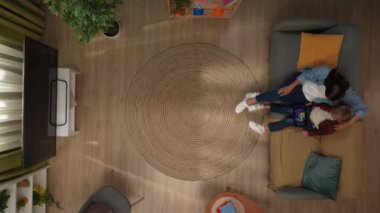 Aile ilişkileri ve ebeveynlik reklamları. Ailecek vakit geçireceğiz. Üst düzey oturma odası anne ve oğlu kanepede oturuyor, çocuk tableti tutuyor ve video seyrediyor, annesiyle konuşuyor..