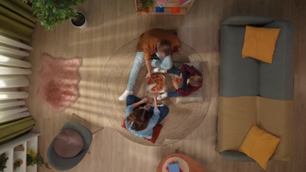 家族関係と親の広告コンセプト 一緒に家族のレジャータイム リビングルームのトップビュー 母親と息子が床に座って大きなピザを食べて一緒に話す — ストック動画