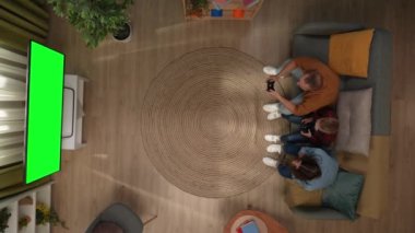 Aile ilişkileri ve ebeveynlik reklamları. Oturma odasının en üst görüntüsü, anne-baba ve oğul kanepede oturup TV 'de krom anahtar yeşil ekranla oyun oynuyorlar, baba oyunu kazandı..