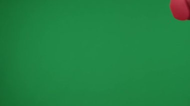 Yeşil arkaplanda, manikürlü topal bir kadın eli müzik dinlemek için kırmızı kablosuz kulaklığı tutuyor ve uzatıyor. İşte reklamınız burada. Orta çerçeve.