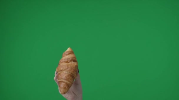 緑色の背景のフレームでは パフペストリーで作られたクロワッサンを透かすマニキュアを施した染色体の女性手 これは ここであなたの広告かもしれません — ストック動画